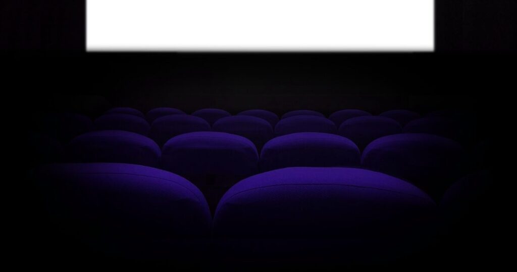 暗闇の映画館で光るスクリーンと座席のシルエット